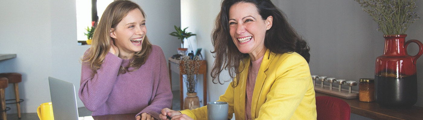 Photograph of two women sitting at a table laughing
