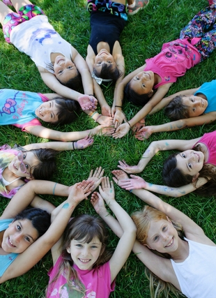 Photograph of children laying on grass in a circular pattern