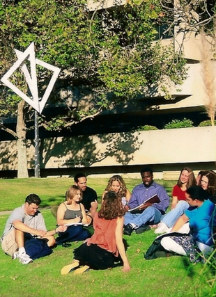 Photograph of art sculpture on lawn with people sitting on ground around it