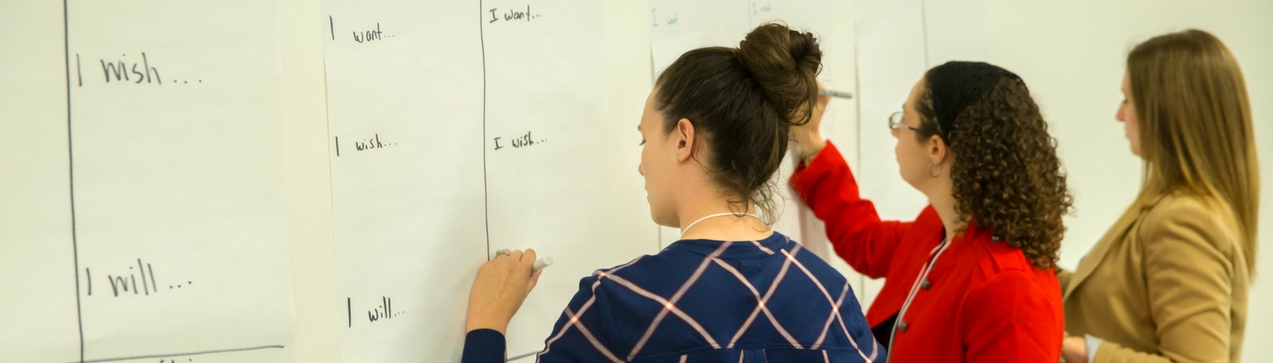 Photograph of three women writing on board