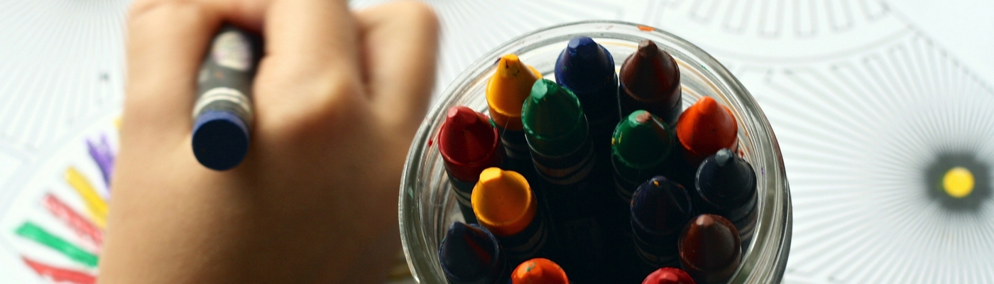 Photograph of crayons in jar and in child's hand