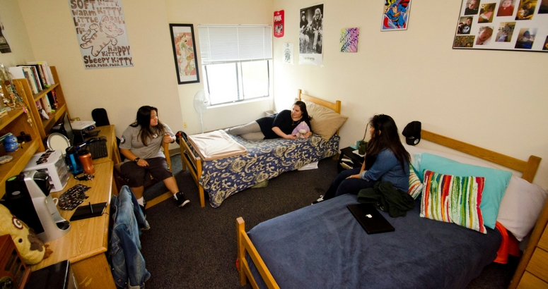 Image of three students hanging out in their dorm room at AJU