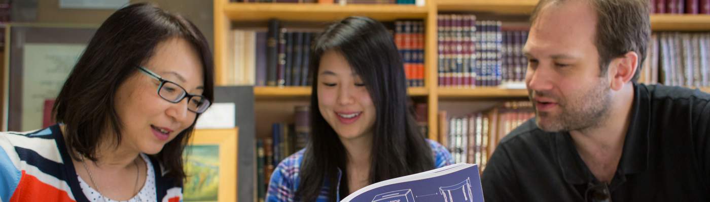 Photograph of two women sitting next to man reading book