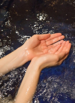 Photo of hands in the mikveh waters