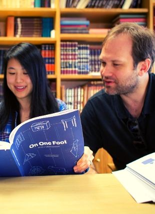 Photo of two students studying from book 