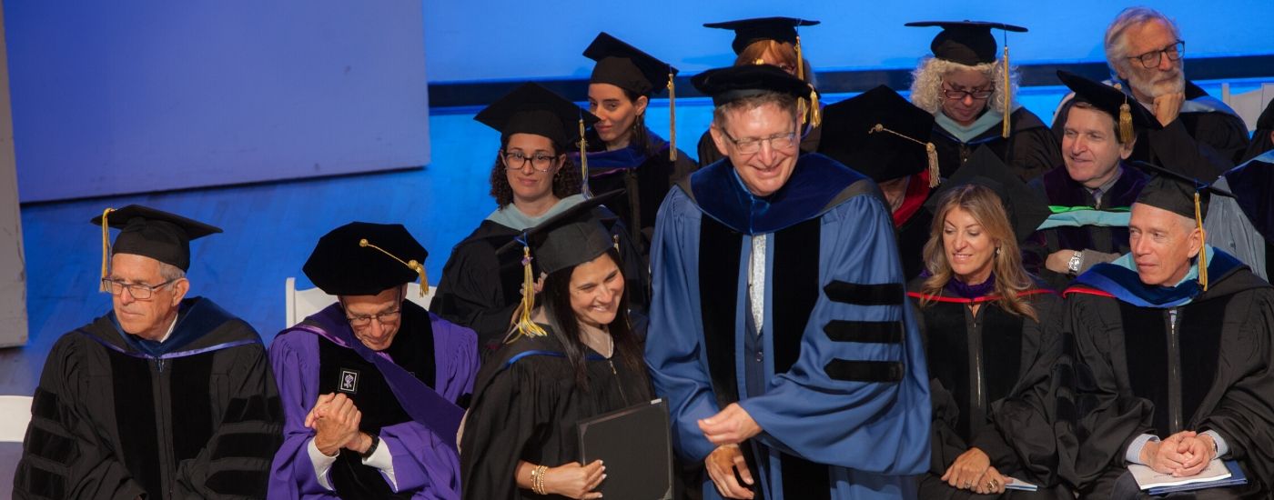 Photo of graduate on stage with faculty