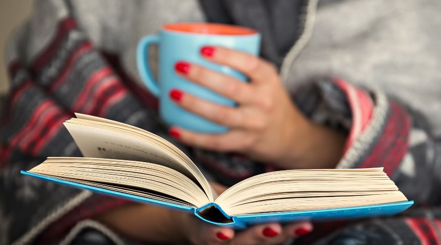 person reading a book with a cup of tea