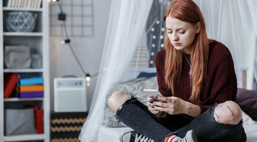 sad teen looking at their phone