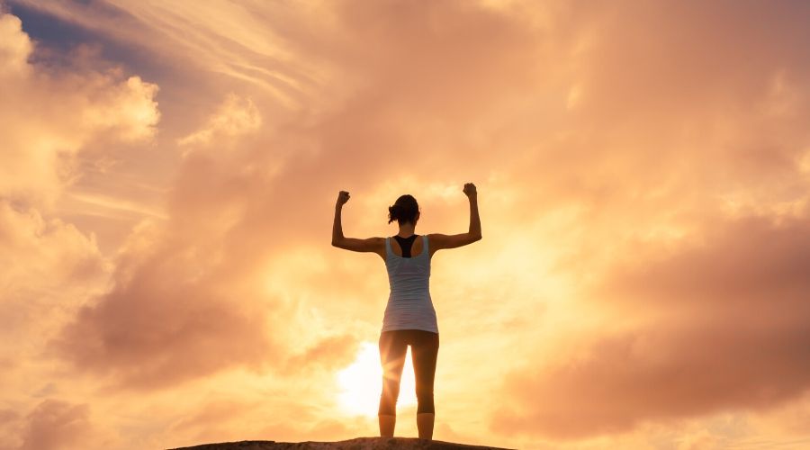 woman standing on a mountain top looking strong