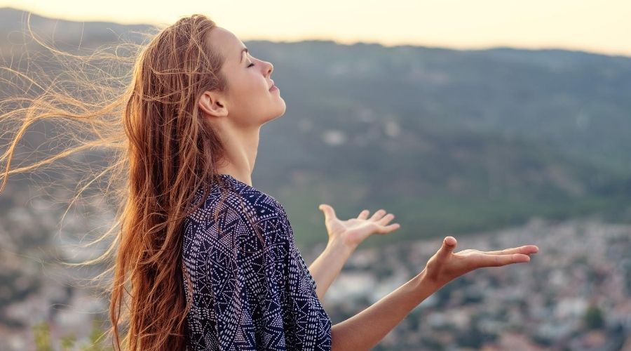 a woman standing outside with her hands raised towards the sky