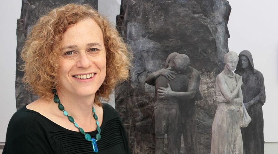 Joy Ladin standing in front of her book cover image