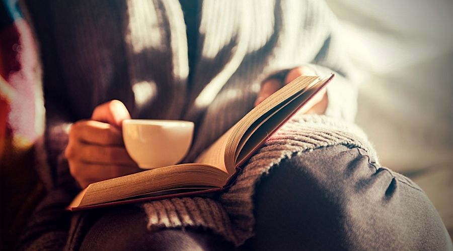 person reading a book with a cup of tea