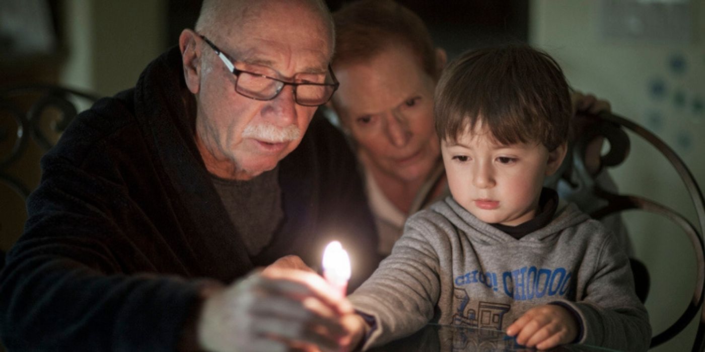 Older couple lighting candle with child