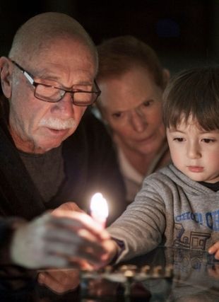 three people lighting a candle