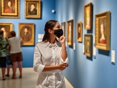 masked woman looking at painting