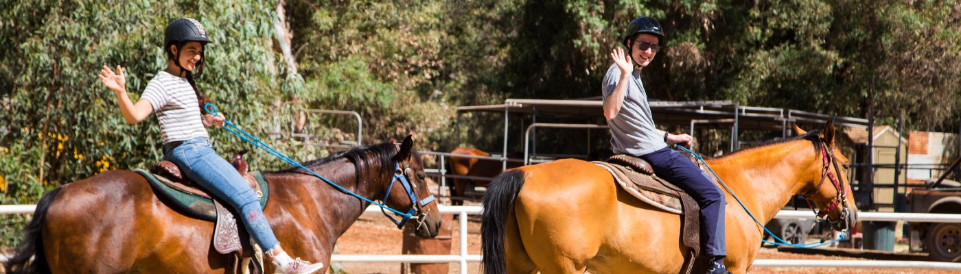 Two BCIers on horses waving at the camera