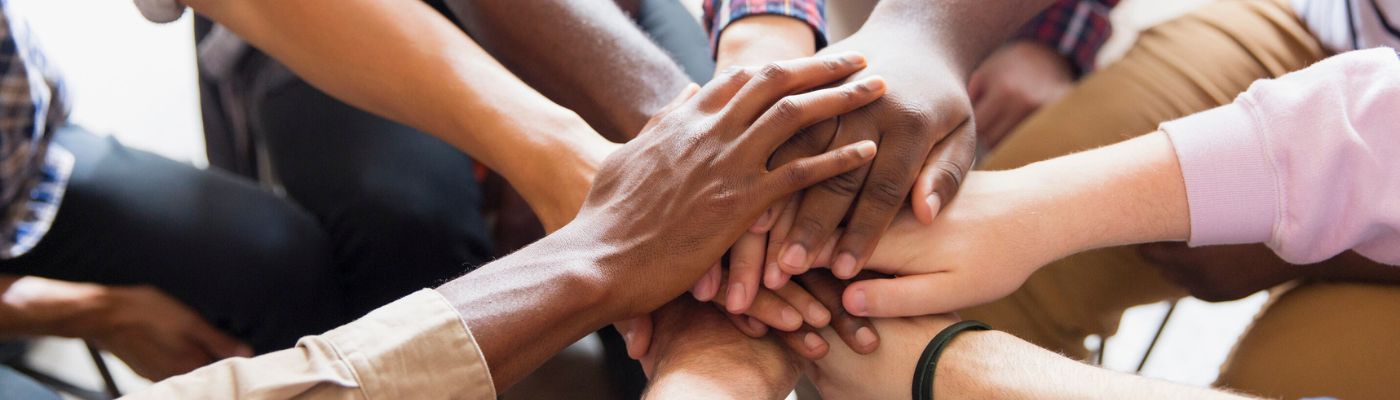 Group of people putting their hands in the middle of the circle