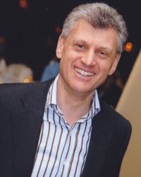 Headshot of Nick Sayers with striped shirt and black jacket