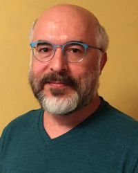 Headshot of Mucahit Bilici with teal shirt and glasses