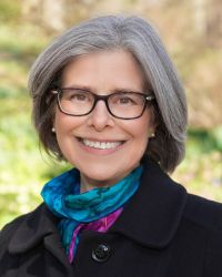 Headshot of Wendy Horwitz in black jacket with pink and blue scarf and glasses