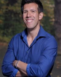 Headshot of Daniel Tam Claiborne in blue button down shirt