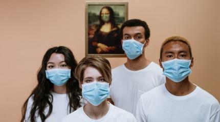 people wearing face masks standing in front of the mona lisa
