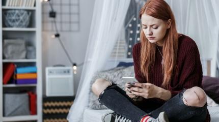 sad teen looking at their phone