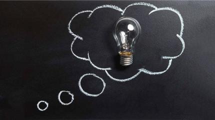a blackboard with a lightbulb inside a think cloud drawn in chalk