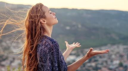 a woman standing outside with her hands raised towards the sky