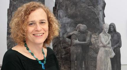 Joy Ladin standing in front of her book cover image
